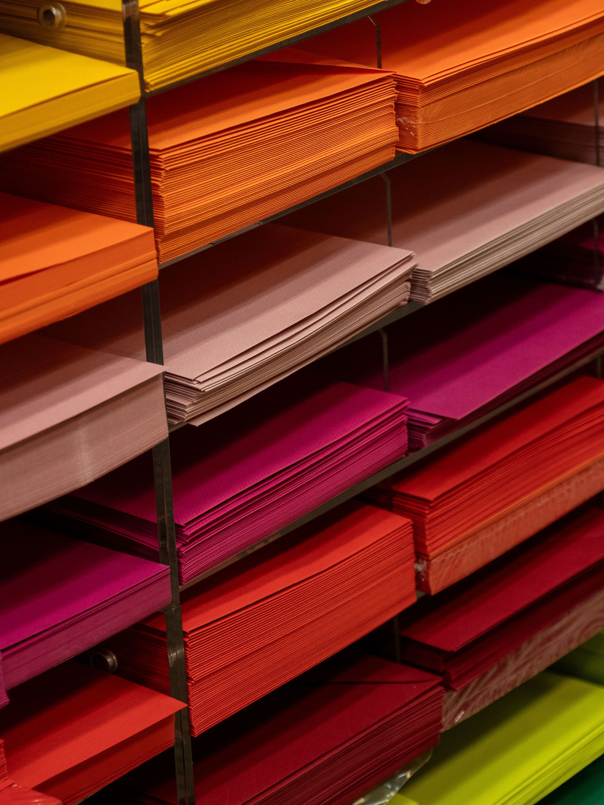 Bright stacks of colorful paper neatly arranged in an office supplies store display.
